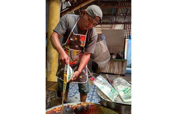KESULITAN MIGOR— Pelaku UMKM saat menuangkan minyak goreng kemasan untuk pengolahan produksi pisang sale.
