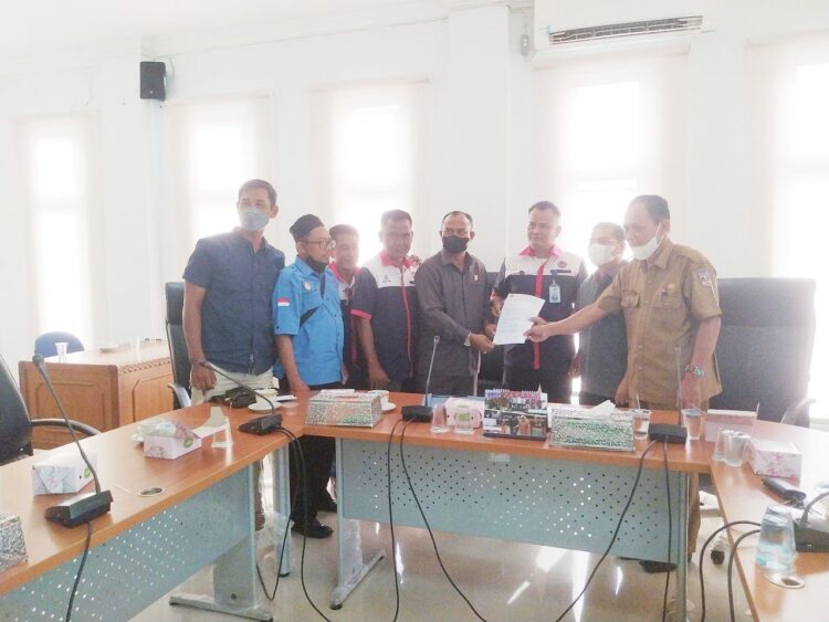 SERAHKAN—Ketua K SPSI Kabupaten Dharmasraya, Firnaldi Rais menyerahkan berkas tuntutan kepada Ketua DPRD, Pariyanto didampingi Wakil Ketua DPRD dan Kadis Transmigrasi dan Ketenagakerjaan Dharmasraya, Kandam usai audiensi yang digelar di Ruang Rapat Komisi I DPRD Dharmasraya.
