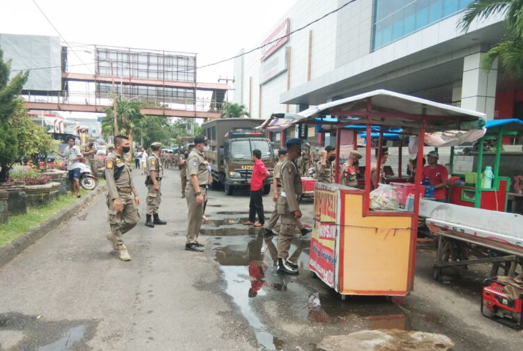 TERTIBKAN PKL — Petugas PKL menertibkan PKL yang masih berjualan 
di area terlarang di depan Ramayana Plaza, Jalan Pemuda, Senin (14/3). Petugas ikut membantu pedagang memindahkan lapak-lapak dagangannya.