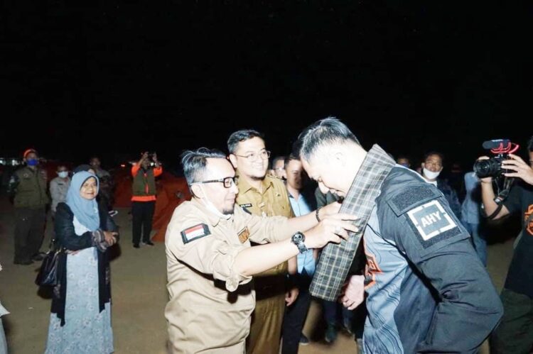 PASANGKAN KAIN SARUNG—Bupati Tanahdatar Eka Putra pasangkan kain sarung pada AHY saat berkemah dengan Komunitas Overlanding, di Puncau Aua Sarumpun.