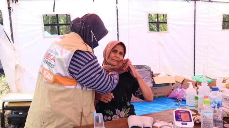 Pengecekan—Relawan ACT mengecek kondisi kesehatan warga korban terdampak gempa di Pasaman Barat.