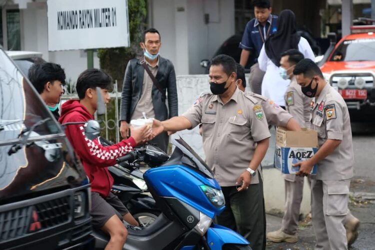 BAGI TAKJIL—Terlihat tim Badan Penanggulangan Bencana Daerah (BPBD) Kesbangpol berbagai takjil kepada pengendara.