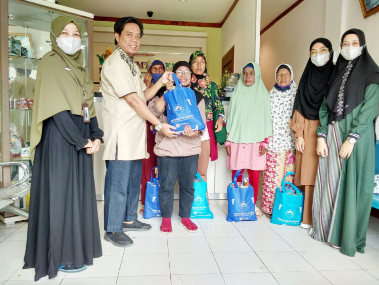 SERAHKAN PAKET SEMBAKO— Edhie Kusmana menyerahkan paket sembako kepada para dhuafa didampingii staf manajemen BMT Al Fataya.