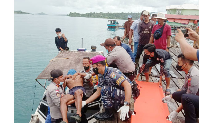 EVAKUASI— Kapolsek Sikakap Iptu Januar menggendong jasad nelayan yang tewas tenggelam saat mencari gurita dari boat ke dermaga usai ditemukan.