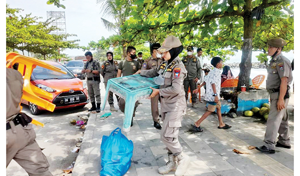 PEMBERSIHAN LAPAK— Tim gabungan Pemko Padang melakukan pembersihan puing-puing dan lapak PKL, Senin (9/5). Petugas Satpol PP juga menemukan sambungan liar dari listrik yang diduga dimanfaatkan pedagang dari tiang-tiang dan yang ada di pinggir trotoar.
