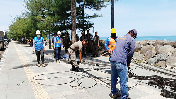 MEMBAHAYAKAN— Tim gabungan Satpol PP Kota Padang membongkar puluhan titik saklar listrik ilegal yang terpasang di pepohonan dan berisiko terhadap keamanan masyarakat, maupun pengunjung Pantai Padang.