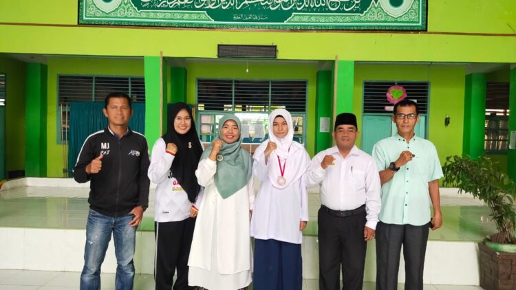 PERUNGGU O2SN— Kepala MTsN 1 Padang Idra Putri (tiga dari kiri)  foto bersama dengan Zyfa Khairani peraih medali perunggu di cabang Karate pada O2SN Kota Padang 2022 yang digelar di GOR Agus Salim.