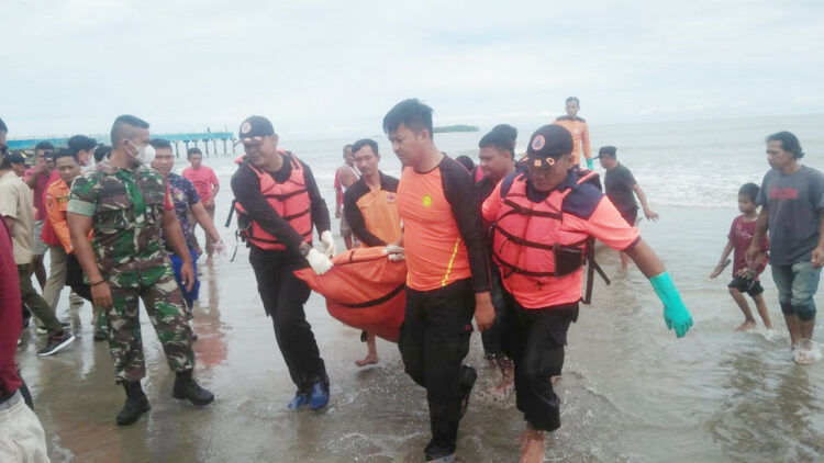 EVAKUASI MAYAT— Petugas BPBD bersama TNI/Polri dan masyarakat sedang menarik perahu yang membawa mayat ke tepi pantai usai ditemukan mengapung di laut.