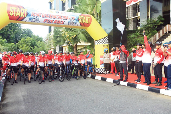 DILEPAS— Kapolda Sumbar Irjen Pol Teddy mengangkat bendera sebagai tanda melepas ribuan pesepeda dalam acara Fun Bike Hari Bhayangkara ke-76.