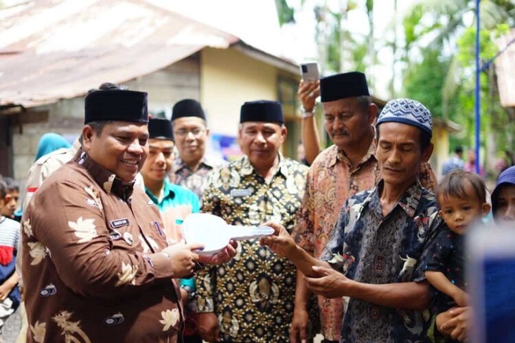 SERAHKAN KUNCI—Bupati Padangpariaman Suhatri Bur serahkan kunci rumah bantuan kepada Junaidi, warga Sunua.