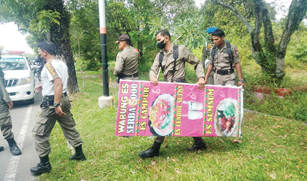 ANGKUT BARANG DAGANGAN — Petugas Satpol PP mengangkut barang dagangan milik PKL yang masih dibiarkan di atas fasilitas umum di jalan S. Parman, Sabtu (11/6).
