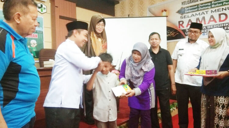 SERAHKAN BANTUAN— Ketua Baznas Padangpariaman Rahmat Tuangku Sulaiman saat menyerahkan bantuan paket kain sarung kepada peserta khitanan massal.