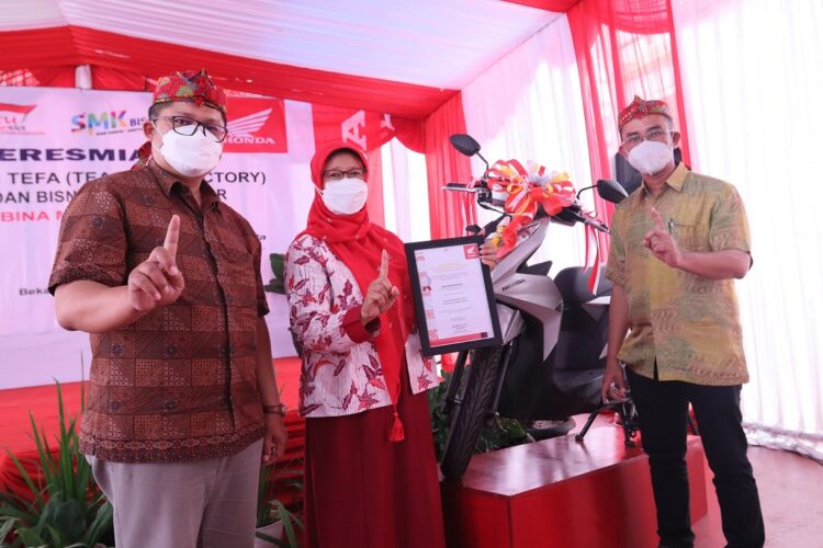 SERAHKAN MOTOR-General Manager Corporate Communication AHM Ahmad Muhibbuddin (Kanan) menyerahkan satu unit sepeda motor Honda BeAT kepada kepala sekolah SMK Bina Mandiri.