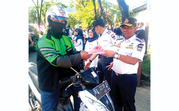 Kadishub Padang Yudi Indra Syani sedang berikan bendera secara garatis kepada pengendara di depan makonya jalan Sutan Syahrir Senin 1 8