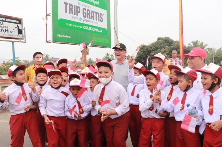 BAGIKAN BENDERA— Wali Kota Ruza Falepi bersama murid-murid SD membagi-bagikan bendera merah putih di jembatan Ratapan Ibu.
