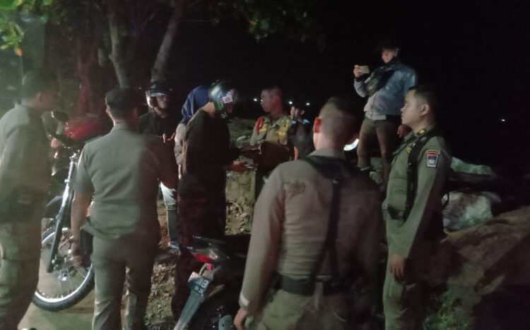 TERJARING RAZIA— Personel Satpol PP Kota Padang mengamankan 4 pasangan remaja saat tengah duduk berduaan di batu grib Pantai Padang, Senin (26/9) malam.