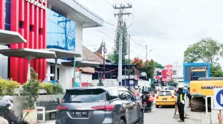 PENGATURAN LALIN— Personel Satlantas Polres Bukittinggi melakukan pengaturan lalu lintas dengan sistem buka tutup di lokasi perbaikan drainase di kota wisata tersebut.