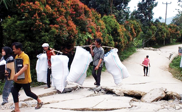 LINTASI— Warga melintasi bagian jalan yang retak akibat pergeseran tanah di Desa Bojong Koneng, Kecamatan Babakan Madang, Kabupaten Bogor, Jawa Barat, Kamis (15/9).