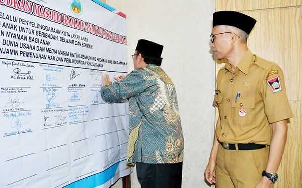 BUBUHKAN TANDA TANGAN— Ketua Dewan Masjid Indonesia Kota Padang Maigus Nasir, melakukan penandatanganan kesepakatan rumah ibadah layak anak bersama para pengurus masjid di Kota Padang, Selasa (13/9).