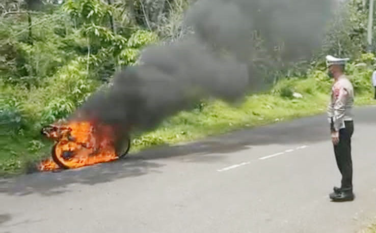 MOTOR TERBAKAR— Terlihat seorang anggota Satlantas mengamankan sepeda motor yang terbakar.