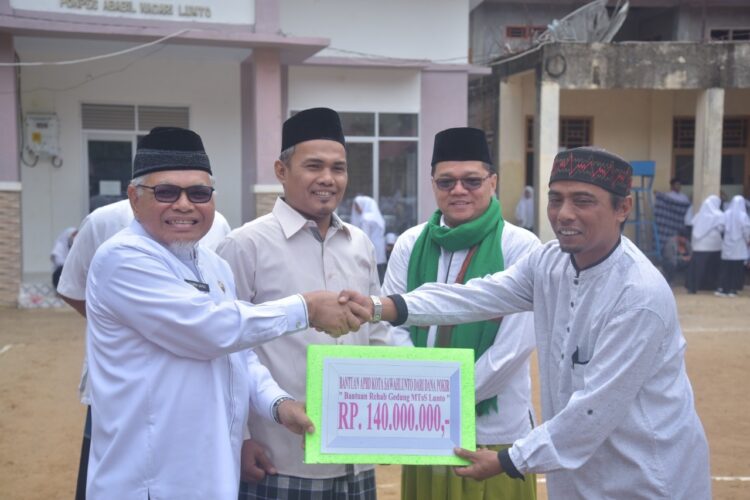 SERAHKAN BANTUAN— Wakil Wali Kota Sawahlunto Zohirin Sayuti didampingi Kakanmenag Sawahlunto Dedi Wandra serahkan bantuan di Peringatan Hari Santri.