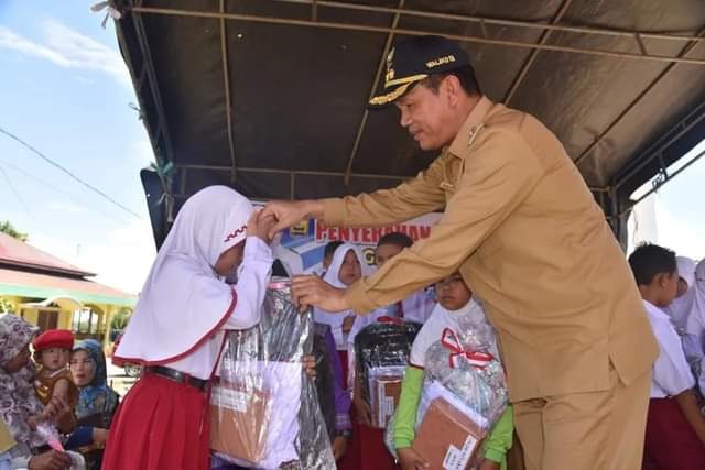 SERAHKAN BANTUAN—Wako Genius Umar  serahkan bantuan pada murid SD.