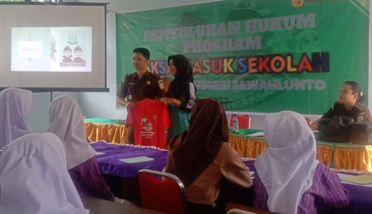 PENYULUHAN HUKUM—Sondang, siswi SMP 2 Sawahlunto menerima hadiah kaos merah dari Tim Jaksa Masuk Sekolah, karena berhasil menjawab pertanyaan.