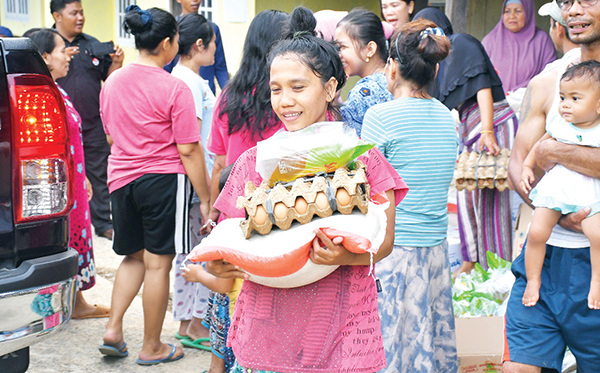 PENGOBAT RASA DUKA— Warga terdampak bencana banjir di Batubusuk, antusias menerima bantuan paket sembako yang diberikan langsung oleh Kepala Unit CSR PT Semen Padang, Rinold Thamrin.