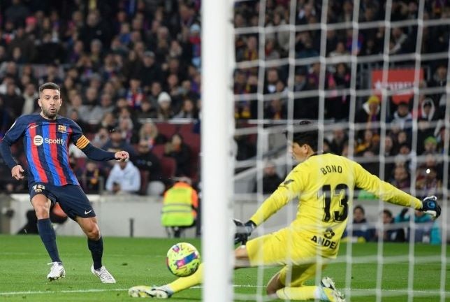 GOL— Bek Barcelona Jordi Alba (kiri) menendang bola untuk mencetak gol pada pertandingan Liga Spanyol melawan Sevilla di Stadion Camp Nou, Barcelona, Senin (6/2) dini hari WIB.
