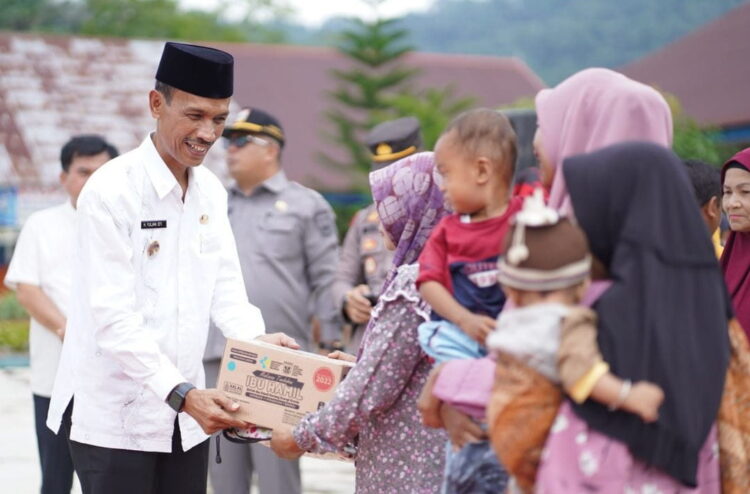 BANTUAN MAKANAN— Wakil Bupati Solsel H. Yulian Efi saat menyerahkan bantuan makanan balita pada seorang warga.
