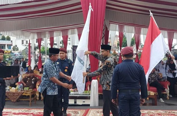 KIRAB PEMILU— Ketua KPU Kota Bukittinggi Satria Putra saat menerima bendera merah putih sebagai lambang prosesi estafet Kirab Pemilu di Indonesia dari Ketua KPU Payakumbuh Khairudin Fambo.