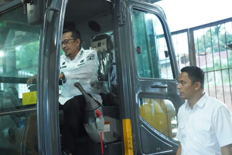 ALAT BERAT—Bupati Tanahdatar  Eka Putra mencoba menaiki alat berat yang digunakan sebagai kesiapsiagaan bencana.