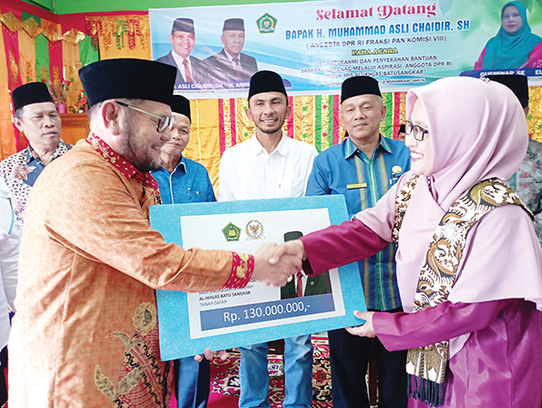 SERAHKAN BANTUAN— Anggota DPR RI Fraksi PAN Asli Chaidir menyerahkan bantuan pembangunan gedung madrasah yang bersumber dari dana pokok pikiran sebesar 130 juta rupiah.