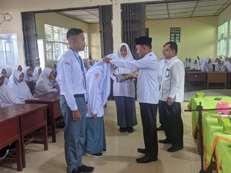 KALUNGKAN TANDA PESERTA—Kepala Kantor KemenagSawahlunto Syafruddin kalungkan pita kepada para peserta siswa baru bertanda dimulainya Matsama Tahun Ajaran Baru 2023/2024.