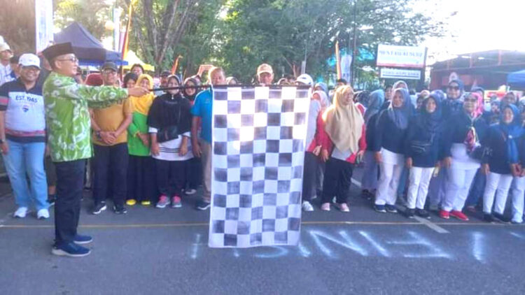 PELEPASAN PESERTA— Wako Hendri Septa mengibarkan bendera saat melepas peserta gerak jalan santai untuk memeriahkan Hari Koperasi ke-76, di depan kantor Diskop UKM, Sabtu (8/7).