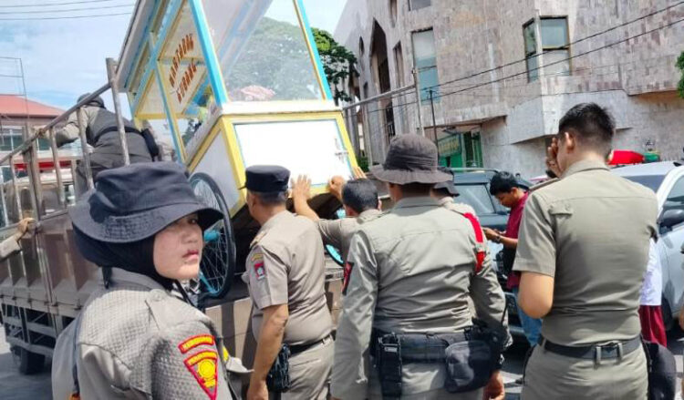 PENERTIBAN— Petugas Satpol PP mengangkut sejumlah gerobak dan payung milik PKL saat dilakukan penertiban di kawasan Pasar Raya Padang. Dalam penertiban Senin itu, masih ada PKL yang nakal dan nekat berjualan di luar jadwal yang sudah ditetapkan.