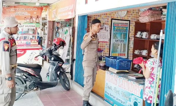 AJAK KIBARKAN BENDERA— Anggota Satlinmas Satpol PP Padang melakukan sosialisasi untuk mengajak masyarakat menggelorakan semangat nasionalisme dan patriotisme, dengan memasang bendera merah putih mulai 1 Agustus hingga 31 Agustus di setiap rumah, toko, ruko, Senin (31/7).
