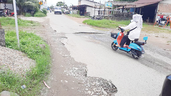 LUBANG BESAR—  Pengendara tampak mengindari lubang besar di jalan Air Paku yang menjadi akses ke RSUD Rasyidin Sungai Sapih, Kota Padang.