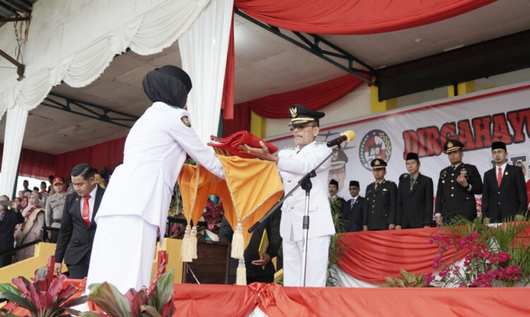 UPACARA— Bupati Limapuluh Kota Safaruddin Dt Bandaro Rajo saat memberikan Bendera Merah Putih untuk dikibarkan pada upacara bendera HUT RI ke-78 di Goor Singa Harau, Lima Puluh Kota.