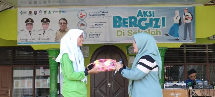 Aksi Bergizi di Sekolah, ”Jangan Pemilu saja, Kepala Daerah harus Selalu Hadir saat Masyarakat Butuh” 1 SERAHKAN—Nny Yusrita Suhatri Bur serahkan bingkisan pada Nabila saat acara kemarin.