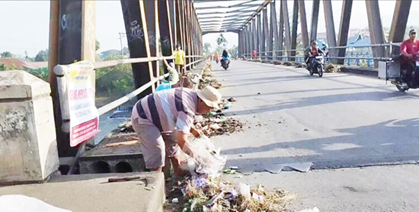 TUMPUKAN SAMPAH— Masyarakat bergotong royong membersihkan tumpukan sampah di areal jembatan Pulau Aia Nan XX, Minggu (30/7). Jembatan yang menghubungkan Kelurahan Parak Laweh Nan XX dengan Gurun Laweh Nan XX ini, kerap dijadikan sebagai tempat pembuangan sampah oleh oknum warga.