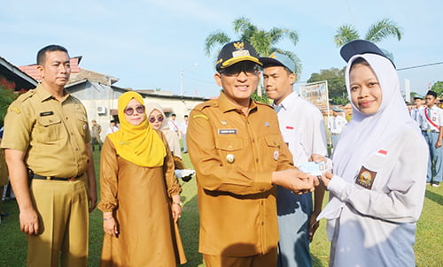 17 Tahun, Wako Beri Siswa SMA PGRI 3 e-KTP 1 SERAHKAN E-KTP— Lia Amelia (17), pelajar SMA PGRI 3 Padang, menerima secara langsung e-KTP yang diserahkan Wako Hendri Septa, di Lapangan SMA PGRI 3 Padang, Kecamatan Padang Selatan, Senin (25/9).
