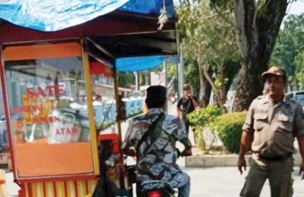 PENERTIBAN PEDAGANG—  Petugas Satpol PP menertibkan pedagang sate yang masih berjualan di atas trotoar, kawasan pedestrian Khatib Sulaiman, Jumat (1/9).