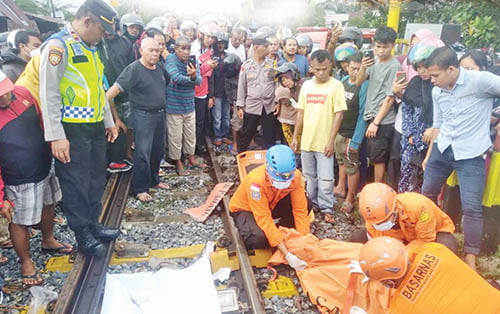 Tragis! Mahasiswa Unand Tewas Ditabrak Kereta Api, Tubuhnya Terpotong jadi Dua Bagian 1 PADANG, METRO
Seorang mahasiswa Universitas Andalas (Unand) tewas tertabrak kereta api saat berjalan kaki di perlintasan tanpa palang pintu dekat perumahan Bumi Lubuk Buaya Indah Lestari, Kecamatan Koto Tangah, Rabu (25/10) sekitar pukul 06.00 WIB.
Korban yang diketahui bernama Fathir Adsar Sofyan (18) yang rumahnya berada tak jauh dari lokasi kejadian, kondisinya sangat mengenaskan. Tubuh korban terpotong menjadi dua bagian setelah ditabrak kereta api dan terseret sejauh 10 meter.
Warga setempat yang melihat ada orang tertabrak kereta api, langsung berdatangan ke lokasi. Setelah dipastikan meninggal dunia, warga yang merasa iba kemudian menutupi tubuh korban yang menggunakan spanduk, daun pisang dan kain. Sedangkan jas almamater Unand milik korban ditaruh di atas tubuhnya.
Tak lama berselang, personel Polsek Koto Tangah datang melakukan olah TKP setelah mendapat laporan adanya kejadian itu. Setelah itu, personel Basarnas Padang juga datang untuk mengevakuasi jenazah korban ke rumah sakit menggunakan mobil ambulans.
Kapolsek Koto Tangah AKP Afrino membenarkan adanya kejadian itu. Menurutnya, korban merupakan warga Perumahan Bumi Lubuk Buaya Indah Lestari yang hendak pergi kuliah ke kampusnya. Namun, saat melintasi rel, korban tertabrak kereta api.
“Korban berjalan kaki menyeberang perlintasan kereta api. Di saat bersamaan, datang kereta api dari arah Padang menuju Kota Pariaman hingga membuat korban tertabrak dan tewas di tempat,” ungkap AKP Afrino ketika dikonfirmasi wartawan.
Melihat kejadian tersebut, dikatakan AKP Afrino, warga stempat lansung melaporkan insiden tersebut ke Polsek Koto Tangah. Pihaknya pun kemudian mendatangi lokasi kejadian untuk mencatat keterangan saksi-saksi dan meminta bantuan Basarnas untuk proses evakuasi.
“Usai dilakukan evakuasi terhadap jasad korban kemudian dilakukan evakuasi dan jasad korban dibawa ke RS M Djamil. Akibat ditabrak kereta api, tubuh korban terpotong menjadi dua bagian. Kaki dan badannya terpisah,” ujarnya.
Sementara itu Kepala Balai Teknik Perkeretaapian (BTP) Kelas II Padang, Supandi menghimbau masyarakat masyarakat untuk bisa lebih waspada dan membudayakan ‘Berteman’ yakni berhenti, tengok kiri, kanan, aman dan jalan.
“Kewaspadaan itu perlu. Kereta api sudah berada di jalurnya. Masyarakat perlu lebih hati-hati dan sayangi nyawanya, menyeberang di pintu perlintasan dan bukan mengambil jalan pintas menyebrang rel di sembarang tempat. Itu sangat berbahaya, seperti kecelakaan tersebut,” tegasnya.
Lebih lanjut katanya, BTP Padang sudah melakukan berbagai cara untuk menekan angka kecelakaan di perlintasan sebidang ini. Seperti melakukan peningkatan prasarana keselamatan sekaligus memberikan sosialisasi pada masyarakat untuk memberikan pemahaman tentang pentingnya berkeselamatan di perlintasan sebidang.
“Kita sudah menutup banyak sekali perlintasan liar, di mana di sana paling banyak terjadi kecelakaan karena tidak terjaga. Kita juga telah membangun POS JPL, palang pintu dan Early Warning System (EWS), patok rel dan pagar ornamen dan beberapa peningkatan lainnya. Namun, semua prasarana tersebut tak akan berfungsi jika masyarakat sendiri tidak aware dengan keselamatan masing-masing,” tambahnya.
Perlu dicatat juga proses BTP Padang dalam melakukan upaya penutupan perlintasan sebidang tersebut bukan tanpa halangan. Sebagai contoh bertahun-tahun BTP Padang melakukan pendekatan kepada masyarakat sekitar Lubuk Buaya dan Tabing agar bisa menutup perlintasan liar. Tidak jarang juga mengalami penolakan serta hambatan dari sebagian masyarakat. Sehingga, barulah pada tahun 2022 BTP Padang berhasil meyakinkan warga untuk melakukan penutupan perlintasan liar tersebut.
“Bertindak sekecil apapun itu lebih bermakna dari pada berwacana tanpa tindakan nyata. Sekali lagi mari bersama sama dengan kami melakukan imbauan gerakan ‘Berteman’ yakni berhenti sejenak, tengok kiri, kanan, aman, lalu jalan. Keselamatan di perlintasan sebidang adalah tanggung jawab kita semua,” tutupnya. (cr2)