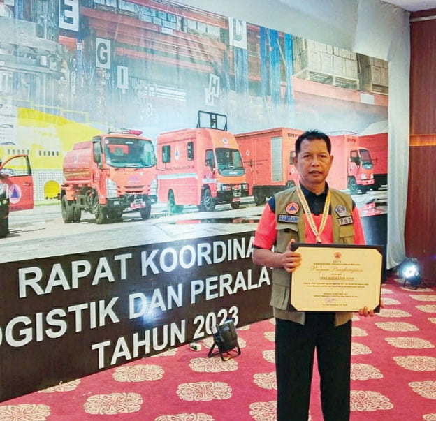 PENGHARGAAN— Kalaksa BPBD Agam, Bambang Warsito memperlihatkan penghargaan pemenang terfavorit kompetisi yel-yel PRB 2023.