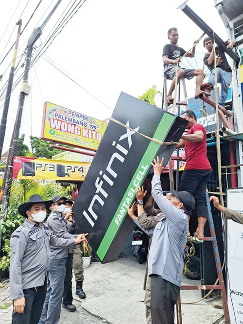 PEMBONGKARAN PAPAN REKLAME— Tim dari Bapenda Kota Padang melakukan pembongkaran terhadap papan iklan yang habis masa tayang di jalan HOS Cokroaminoto, Kecamatan Padang Barat, Kamis (19/10).