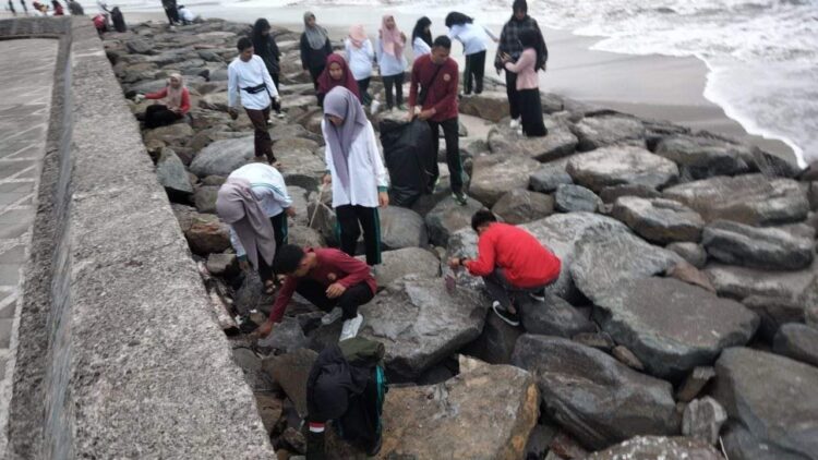 BERSIHKAN PANTAI— Pj Wako Pariaman Roberia saat aksi bersih-bersih di Pantai Gandoriah.
