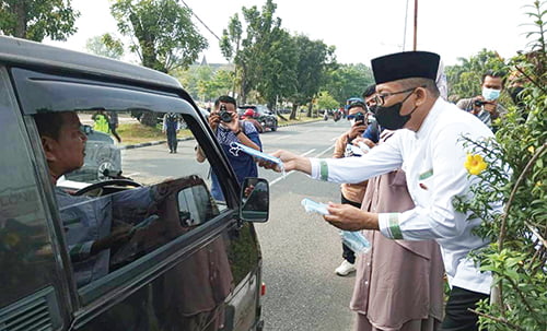 BAGIKAN MASKER— Wako Padang Hendri Septa membagikan masker kepada pengendara dan warga dalam aksi peduli di depan Masjid Raya Sumbar, Jumat (20/10). Jika dalam beberapa hari ke depan, kondisi kabut makin parah, wako akan mempertimbangkan siswa belajar daring di rumah.