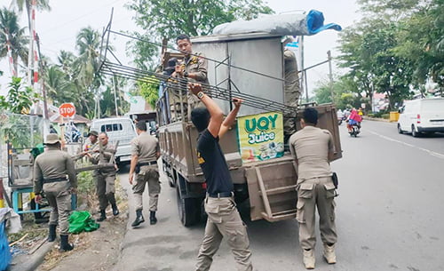PENERTIBAN— Petugas Satpol PP mengangkut gerobak, payung, meja dan kursi milik PKL yang berjualan di trotoar dan badan jalan saat dilakukan penertiban, Senin (23/10).