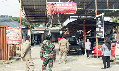 Lagi, Belasan Penunggak Dihadiahi Spanduk ”Tidak Taat Pajak” 1 BELUM LUNASI PAJAK— Petugas gabungan Bapenda Kota Padang memasang spanduk di salah satu usaha milik Wajib Pajak (WP) yang belum melunasi pajak, Kamis (16/11). Pemasangan spanduk dilakukan untuk memberi efek jera kepada pemilik, sehingga segera melunasi kewajibannya.